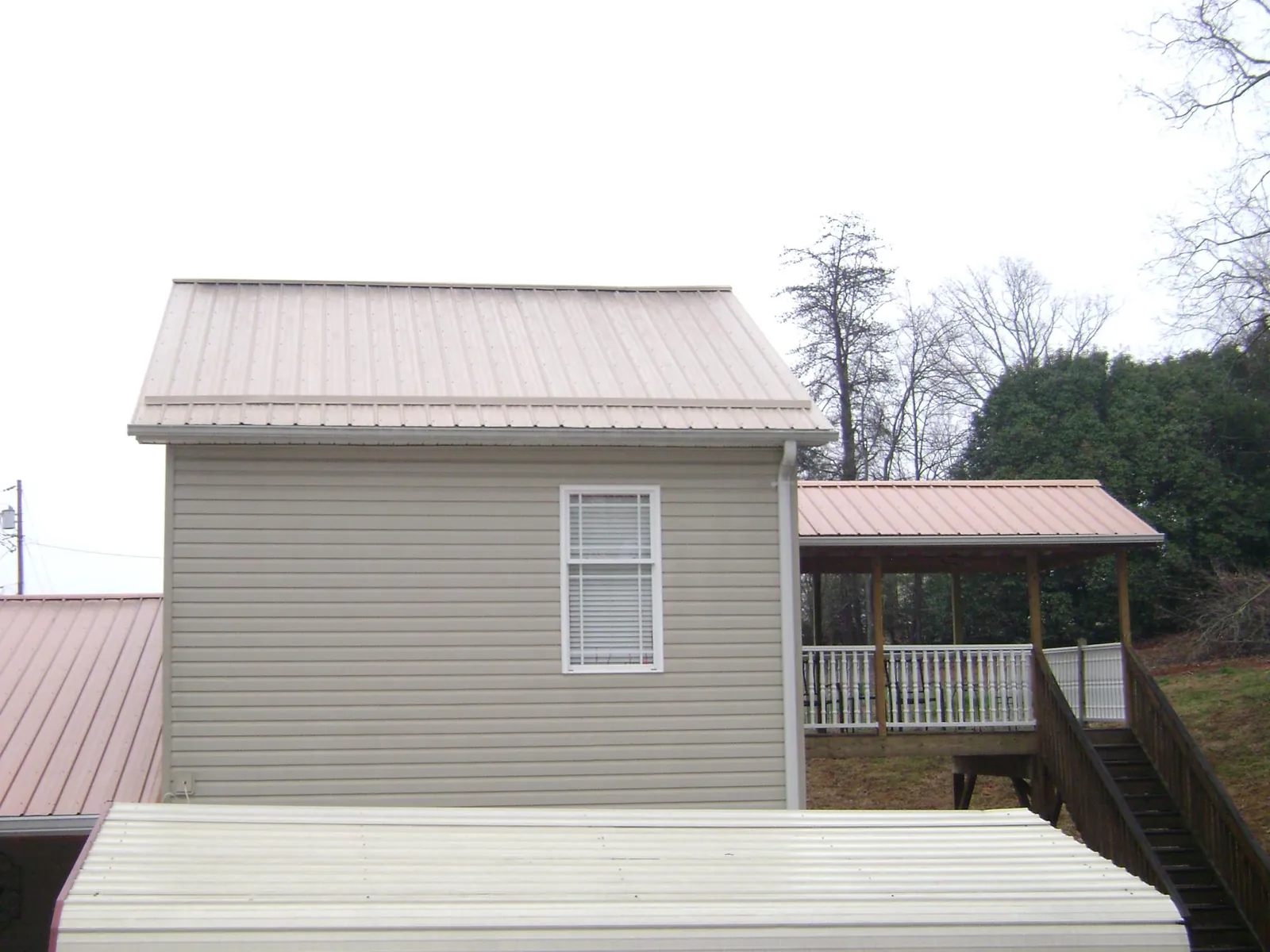 Tan metal roofs on a two story addition and attached porch, from a Roof Replacement job in Garden Grove